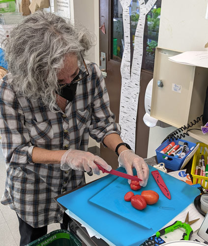 PS118 teacher preparing tomatoes to taste.
