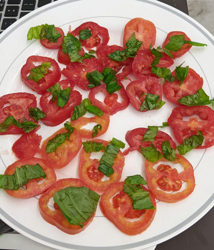 A plate of tomatoes and basil.